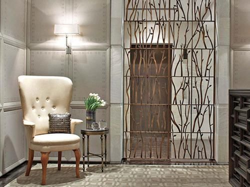 Elegant room with cream tufted chair, side table, wall sconce, and decorative metal screen.