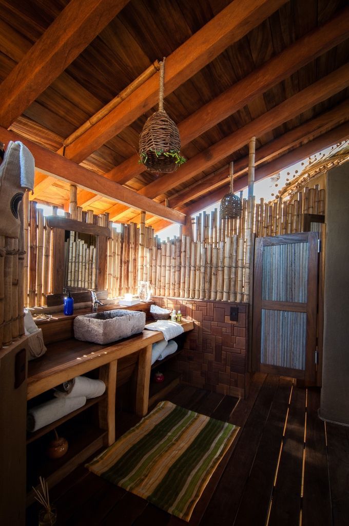 Rustic wooden patio with open roof beams, bamboo walls, table, chairs, and striped rug in warm light