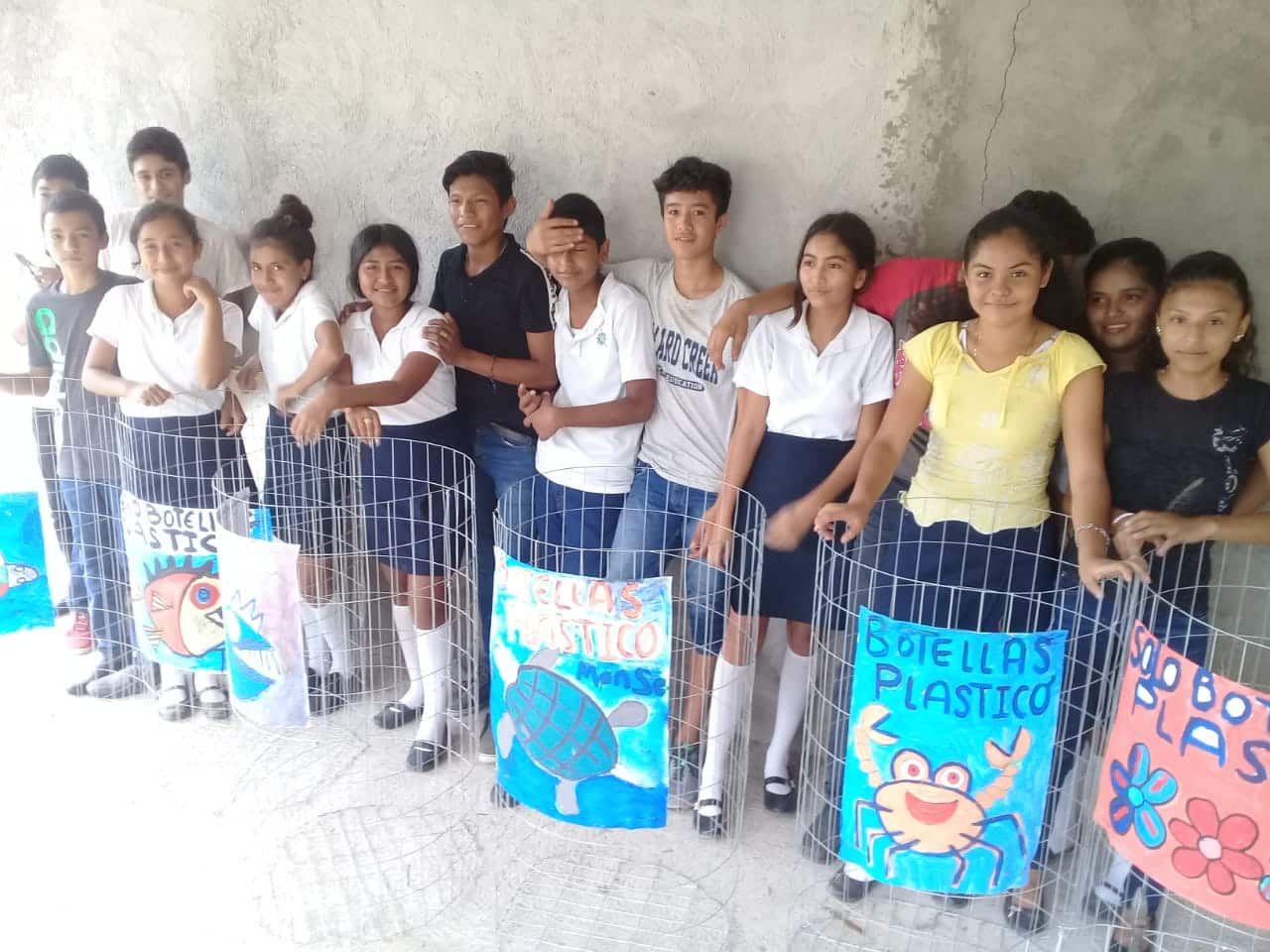 Group of students standing in a row indoors, holding colorful handmade posters.