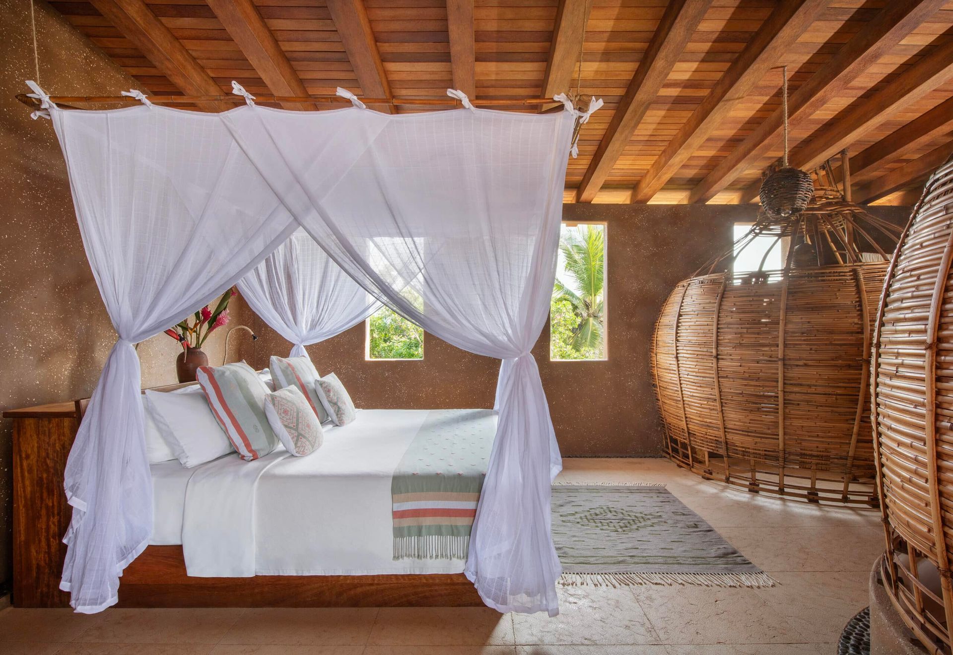 White canopy bed in a rustic bedroom with wood ceiling and wicker decor