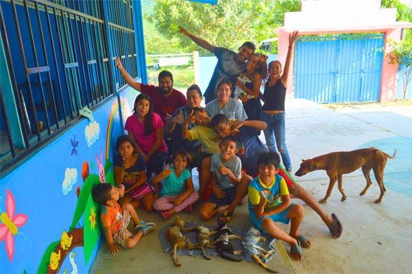 Group posing by a blue wall with two dogs in a sunny courtyard