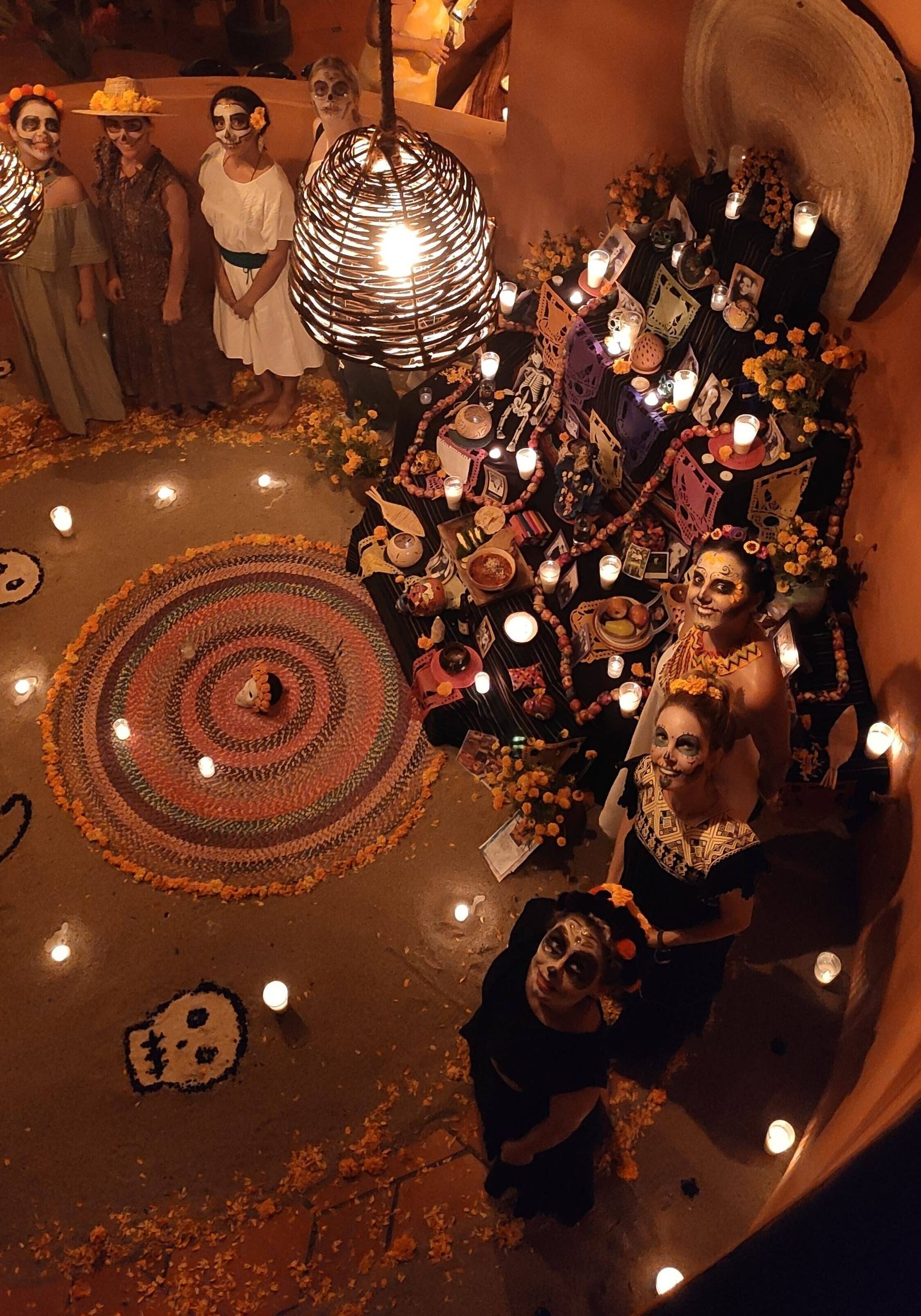 Crowded festive gathering around a large circular decor with candles and ornate hanging lights