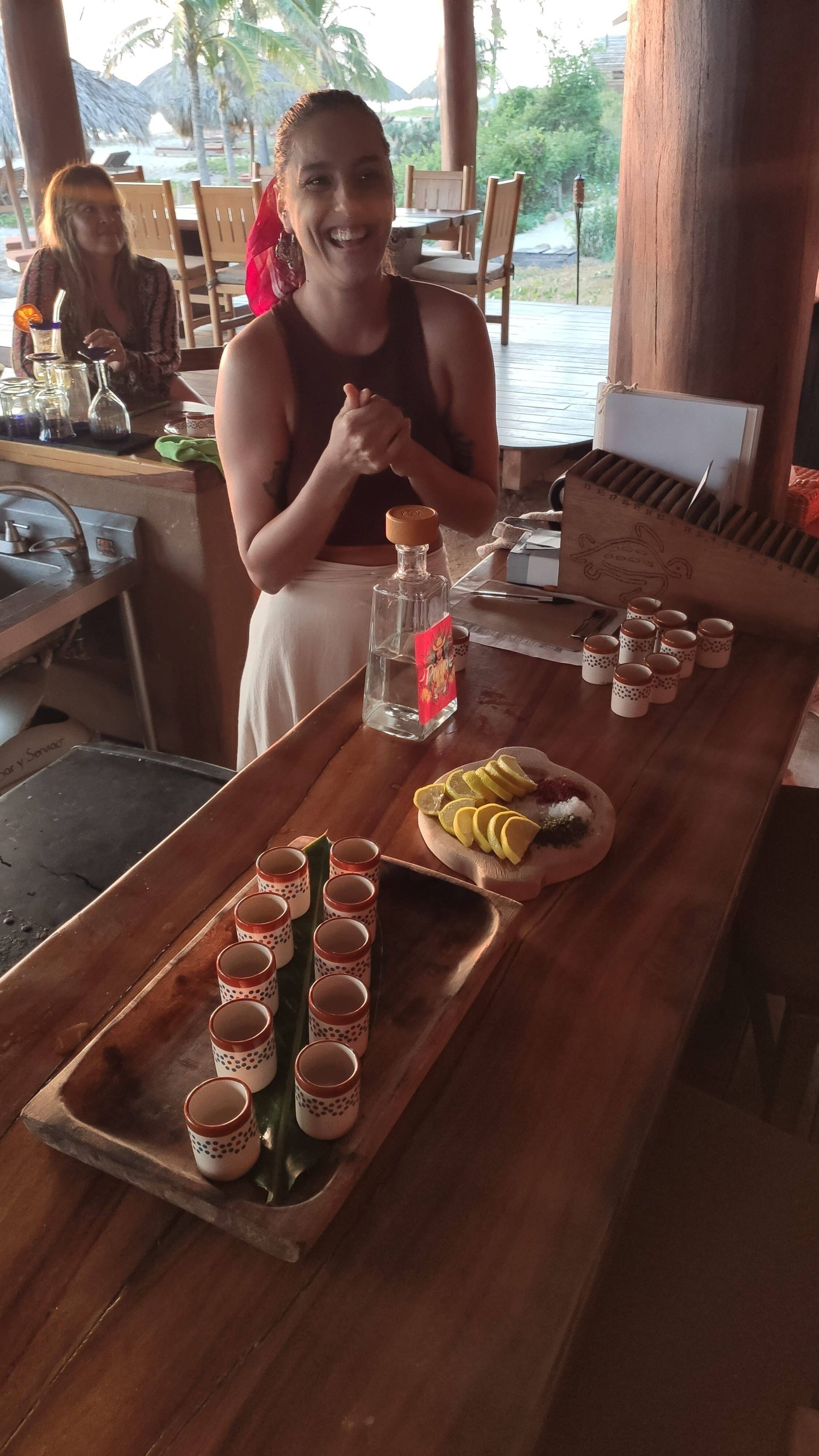 Woman smiling at a wooden table with cupcakes and a drink in a rustic outdoor café