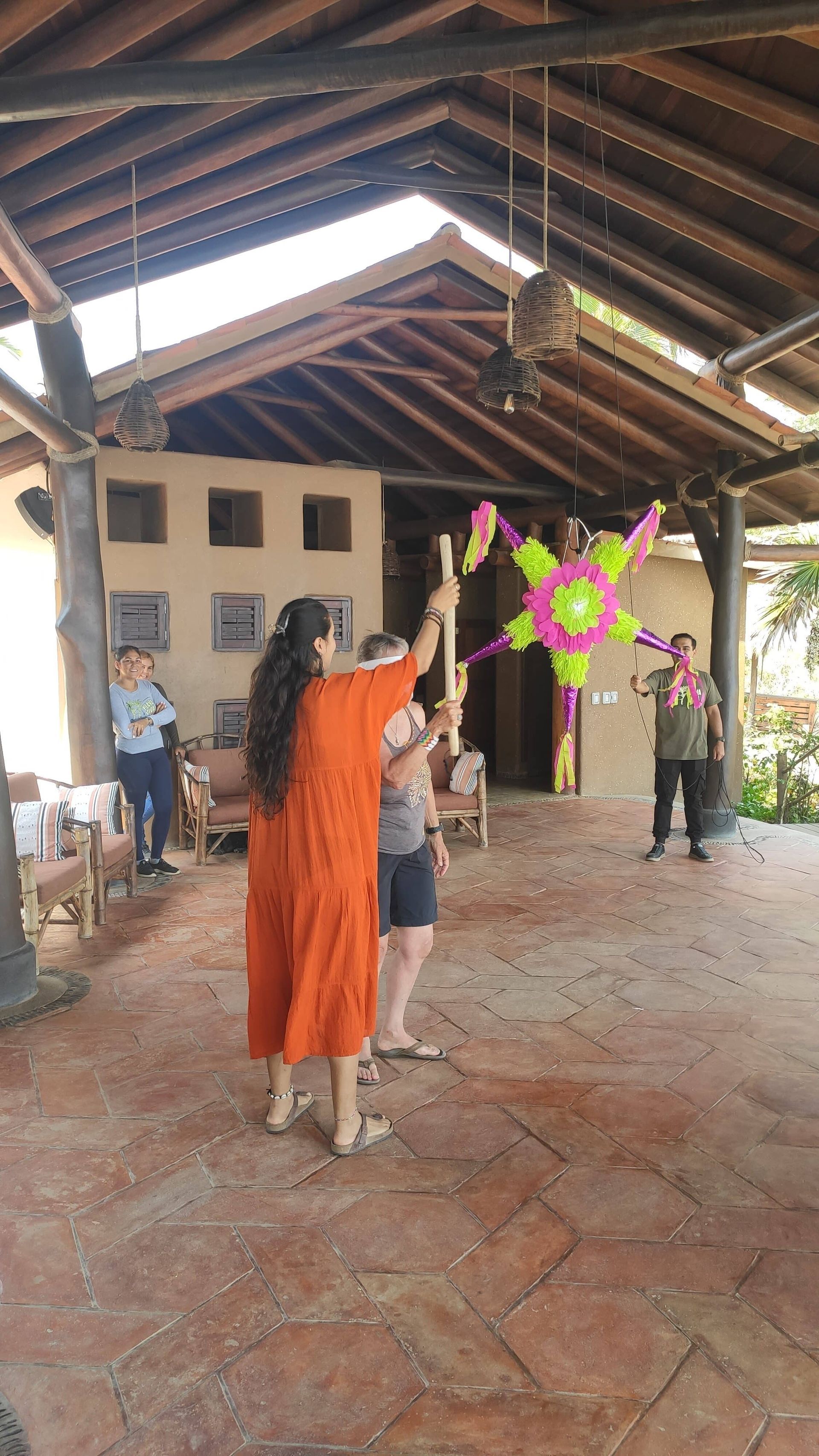 People in a pavilion play a lively indoor game with a colorful star-shaped hanging target.