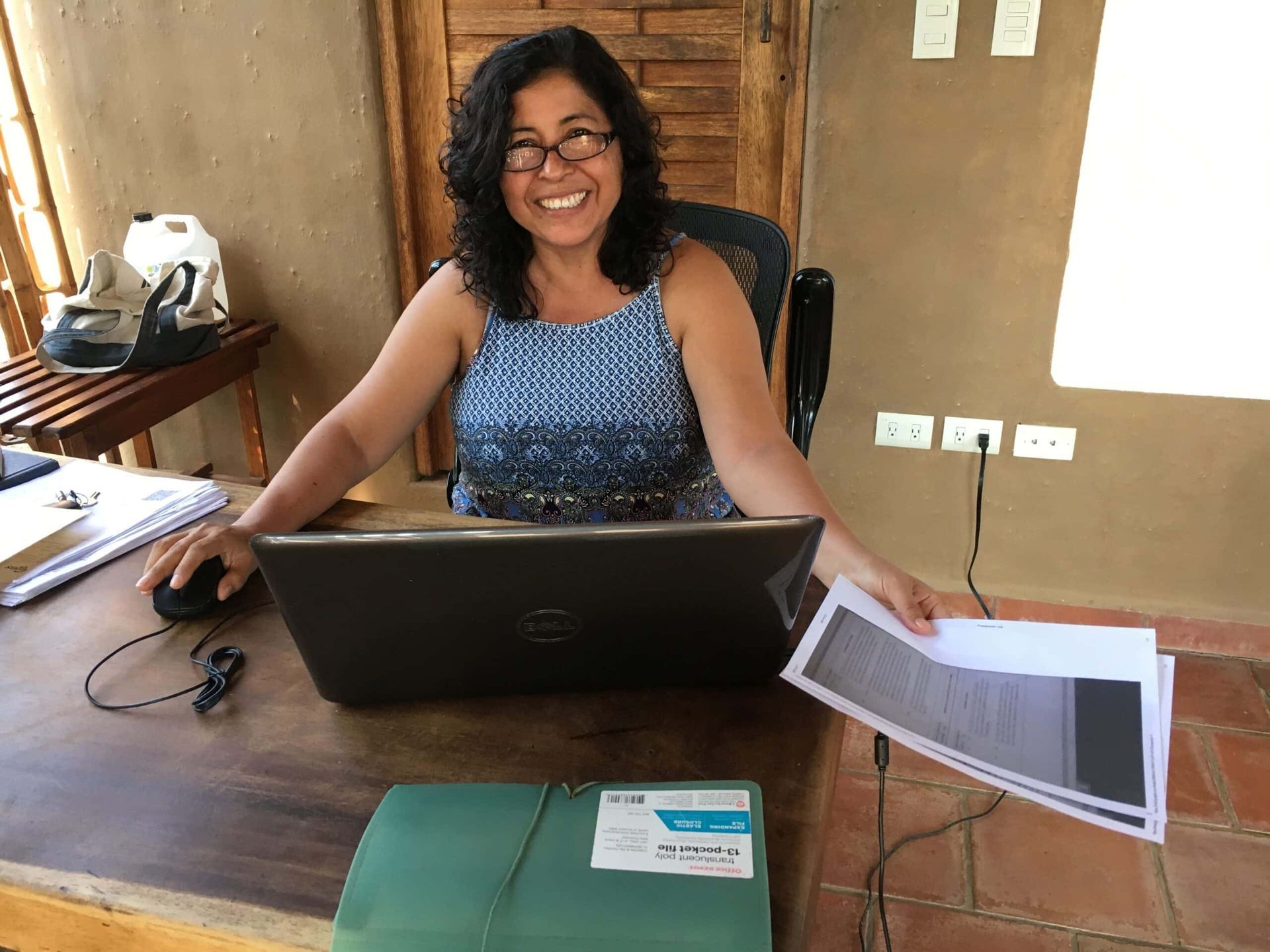 Smiling woman at a desk with a laptop in a wood-paneled office