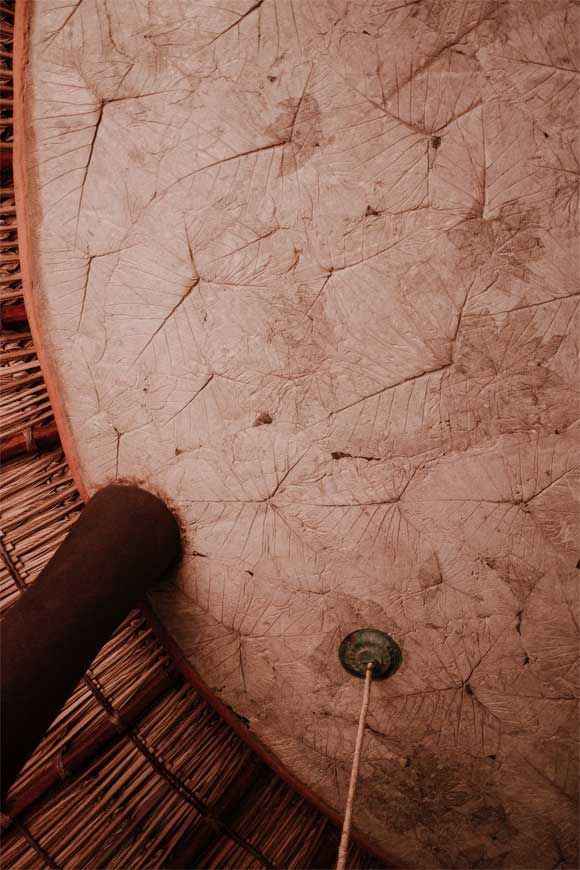 Close-up of a cracked white lampshade with a pull cord against a woven chair background
