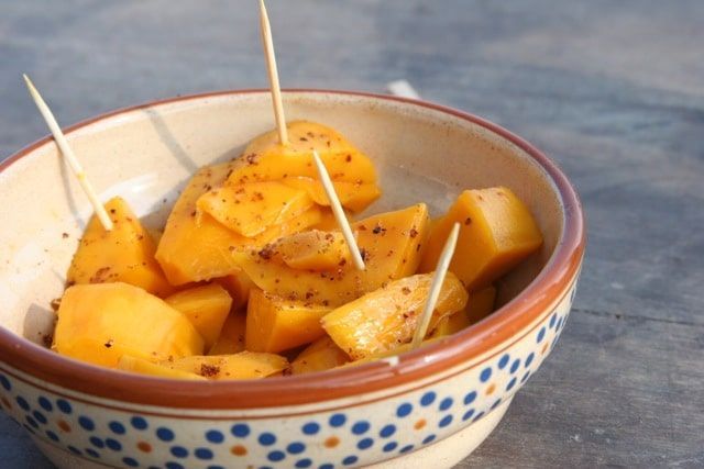 Bowl of cubed mango pieces topped with toothpicks, sprinkled with seasoning