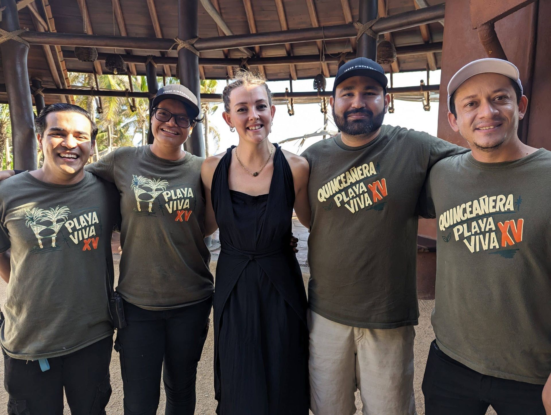Five smiling staff members in matching T-shirts standing together inside a rustic building
