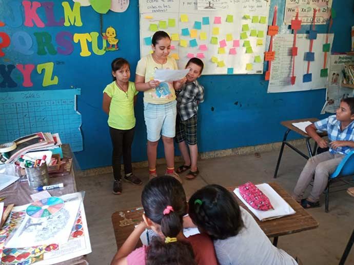 Children presenting in a colorful classroom while classmates watch at desks