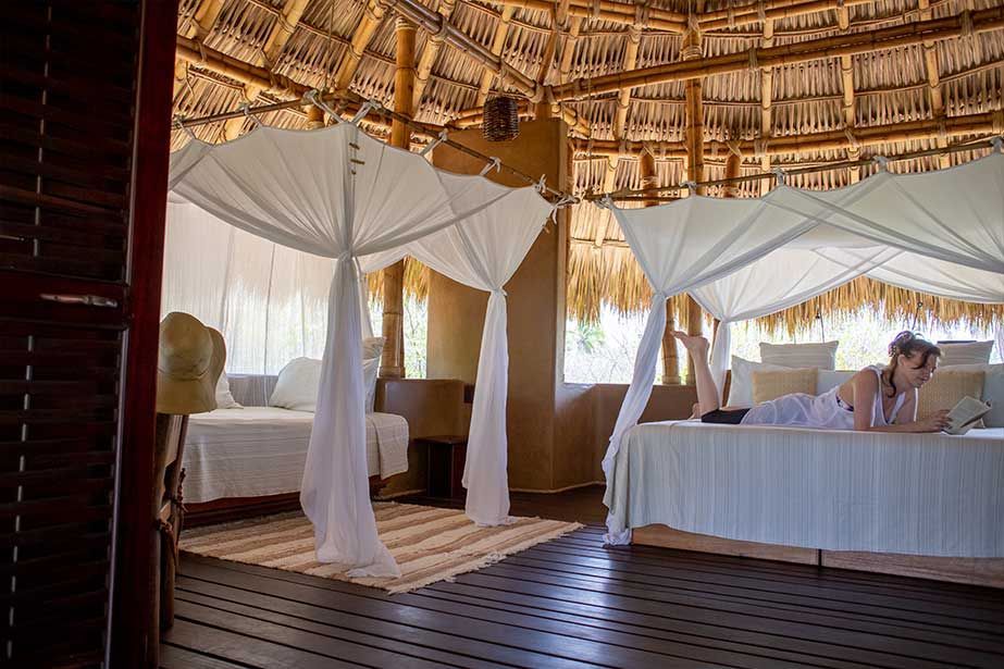 A woman is laying on a bed under a canopy.