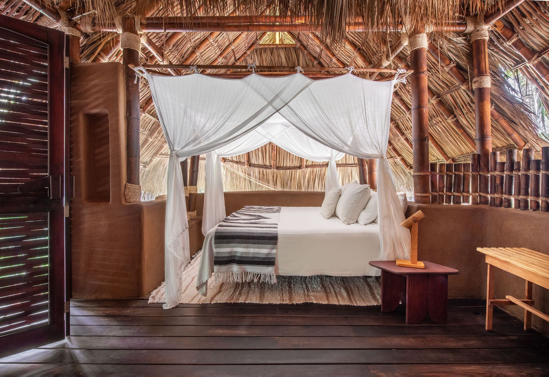 A bedroom with a canopy bed and a thatched roof.