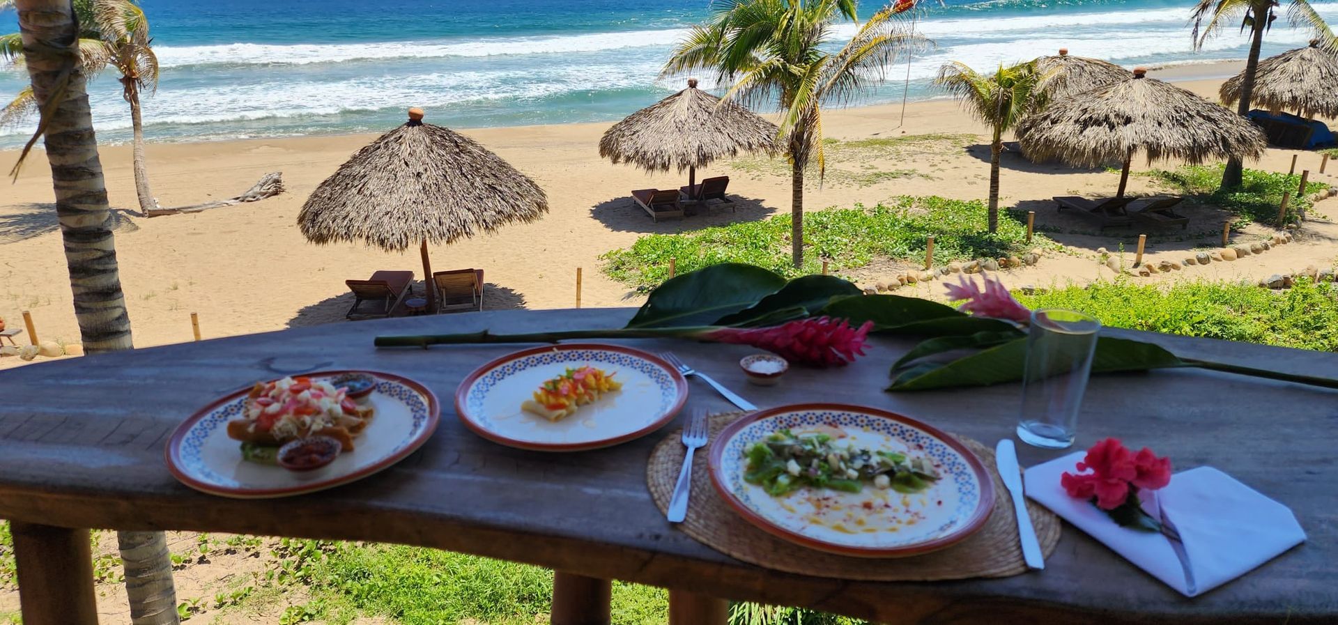 Beachside table with plated seafood dishes overlooking umbrellas and the ocean
