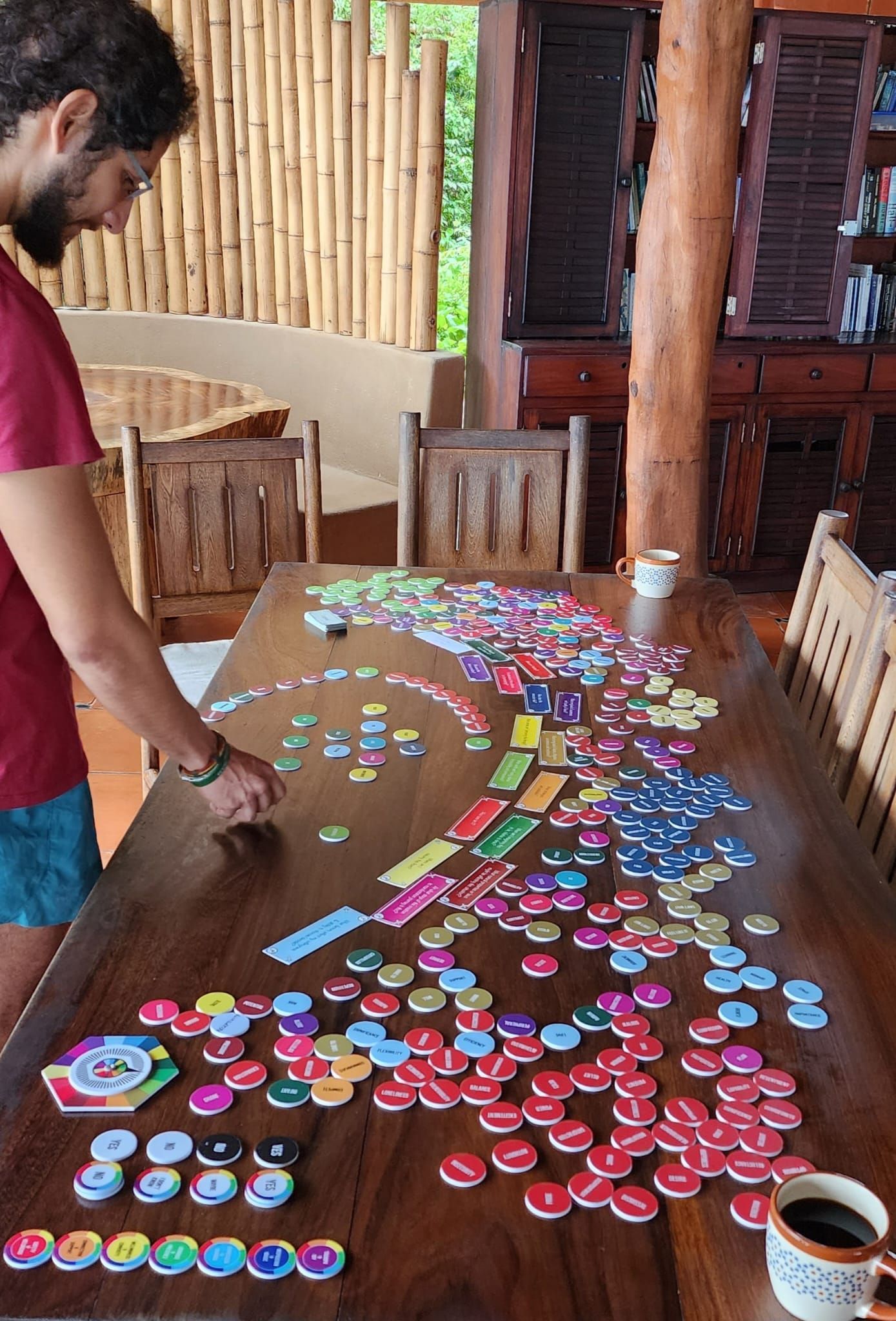 Person arranging colorful bottle caps into patterns on a wooden table indoors