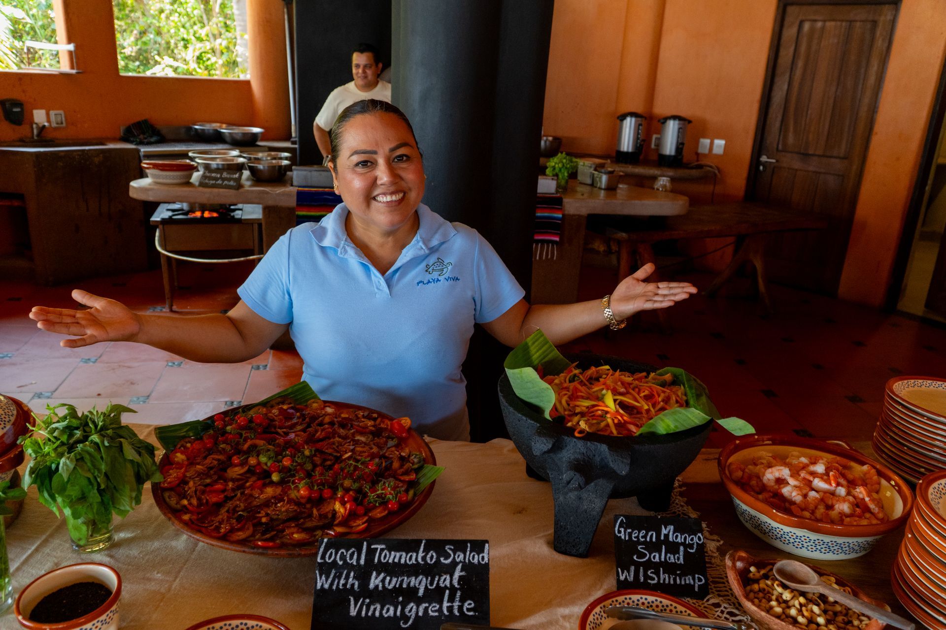 a team member proudly presenting an abundant buffet of farm to table food 