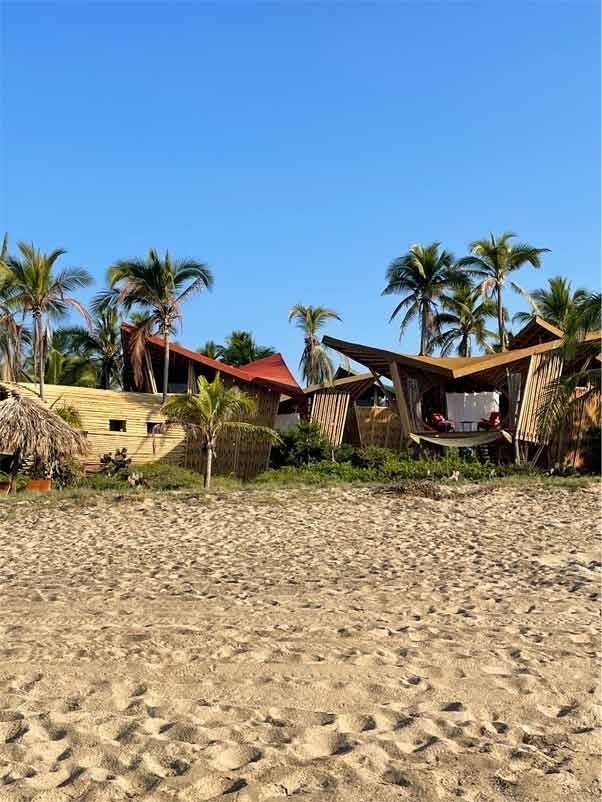 Sandy beach with thatched huts and palm trees under a clear blue sky
