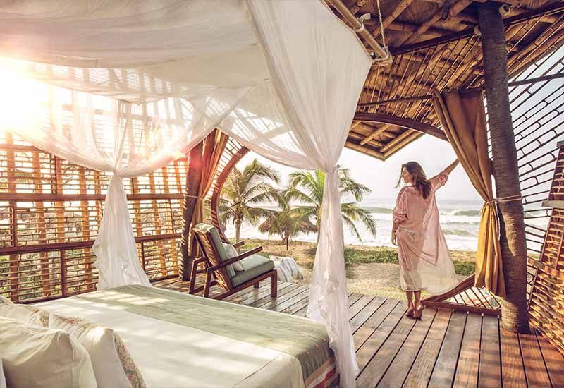 A woman is standing on a balcony overlooking the ocean.