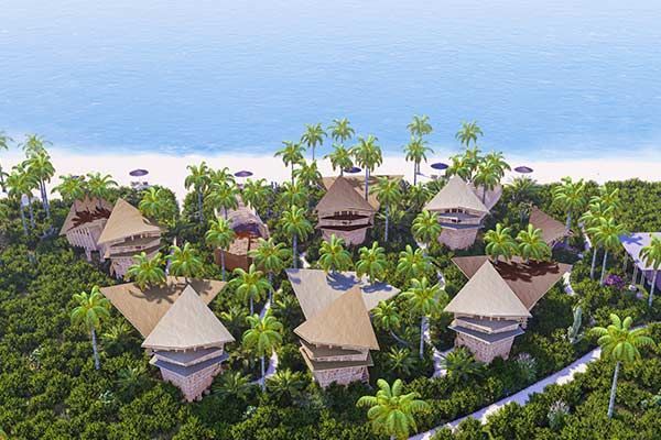 Aerial view of tropical resort villas with thatched roofs surrounded by lush palms and ocean.