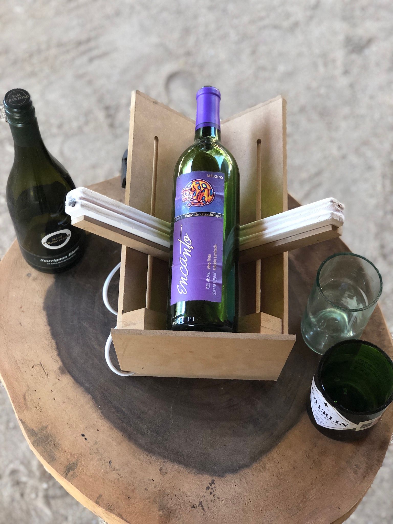 Wine bottles and glasses arranged in a cardboard carrier on a round table