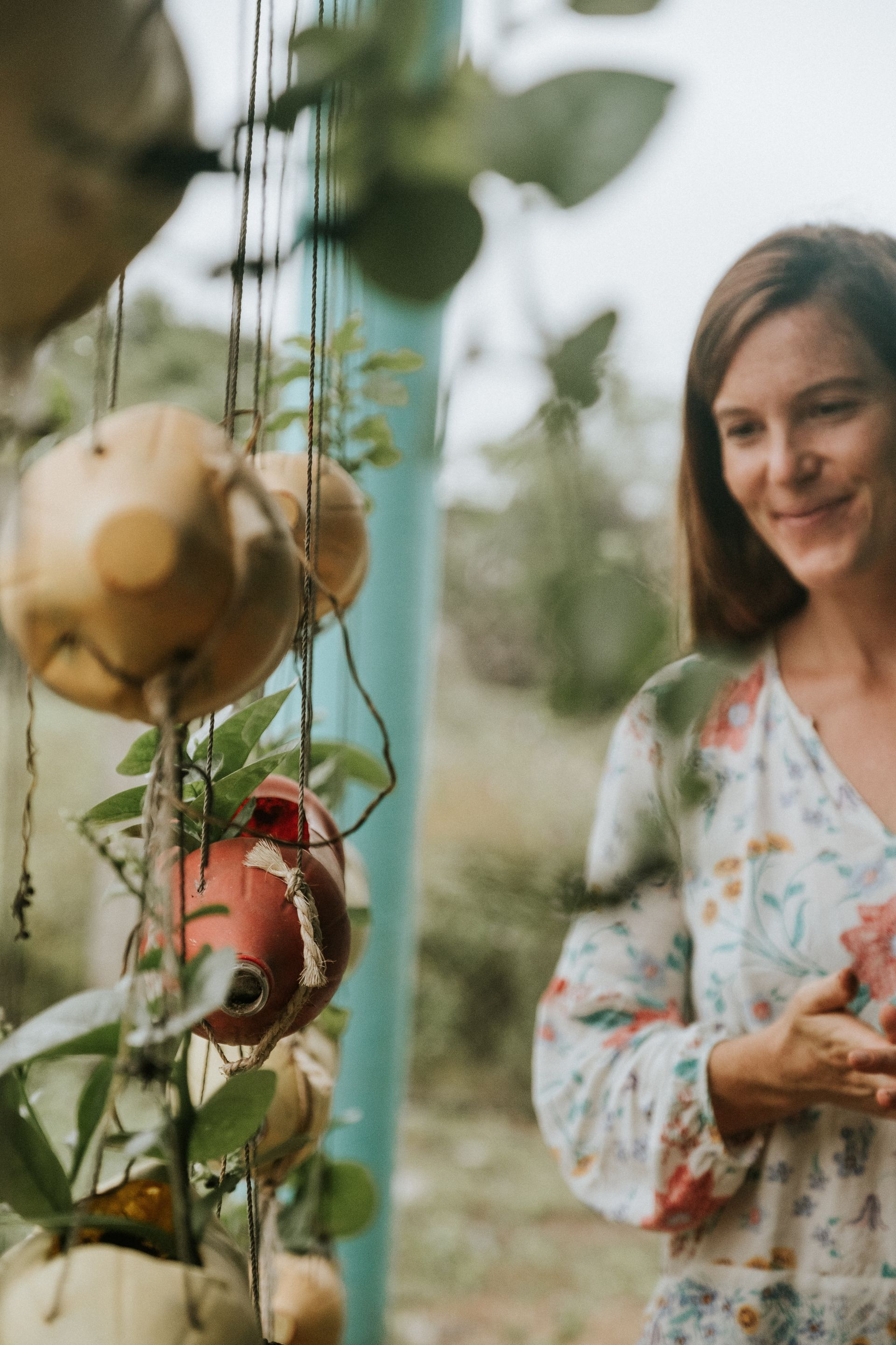 Woman smiling beside hanging tomatoes in a garden