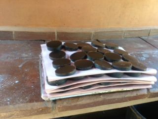 Stack of white papers with several dark round objects on top, resting on a wooden surface.