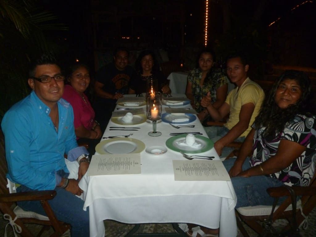 Group of friends seated around a candlelit dining table in a dim restaurant