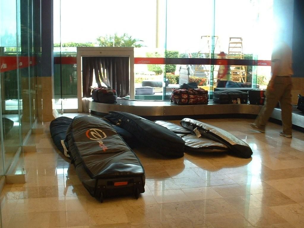 Three black luggage bags on a glossy floor near a glass storefront.