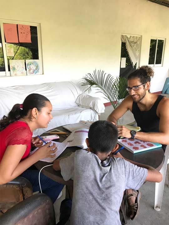 Three people sit around a table playing a board game in a living room.
