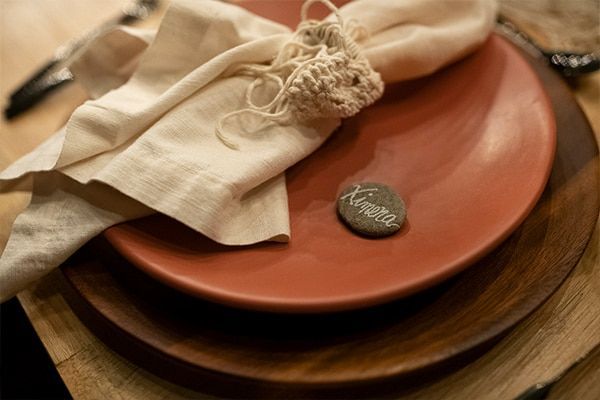 Folded napkin with twine on terracotta and wooden plates at a rustic table setting