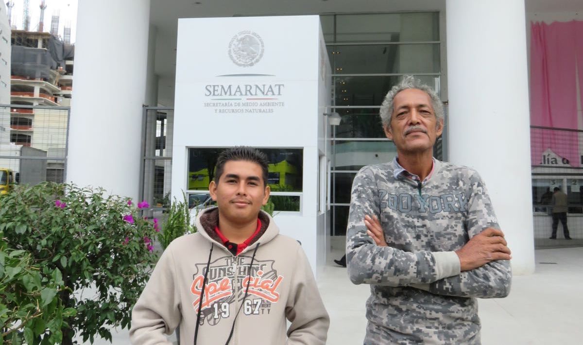 Two people standing outside a modern building with a SAMARIT logo, one in a hoodie and one in a patterned shirt.