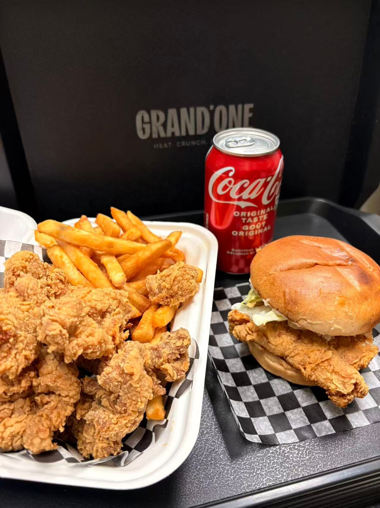 Fried chicken meal with fries, sandwich, and a Coke on a checkered tray table