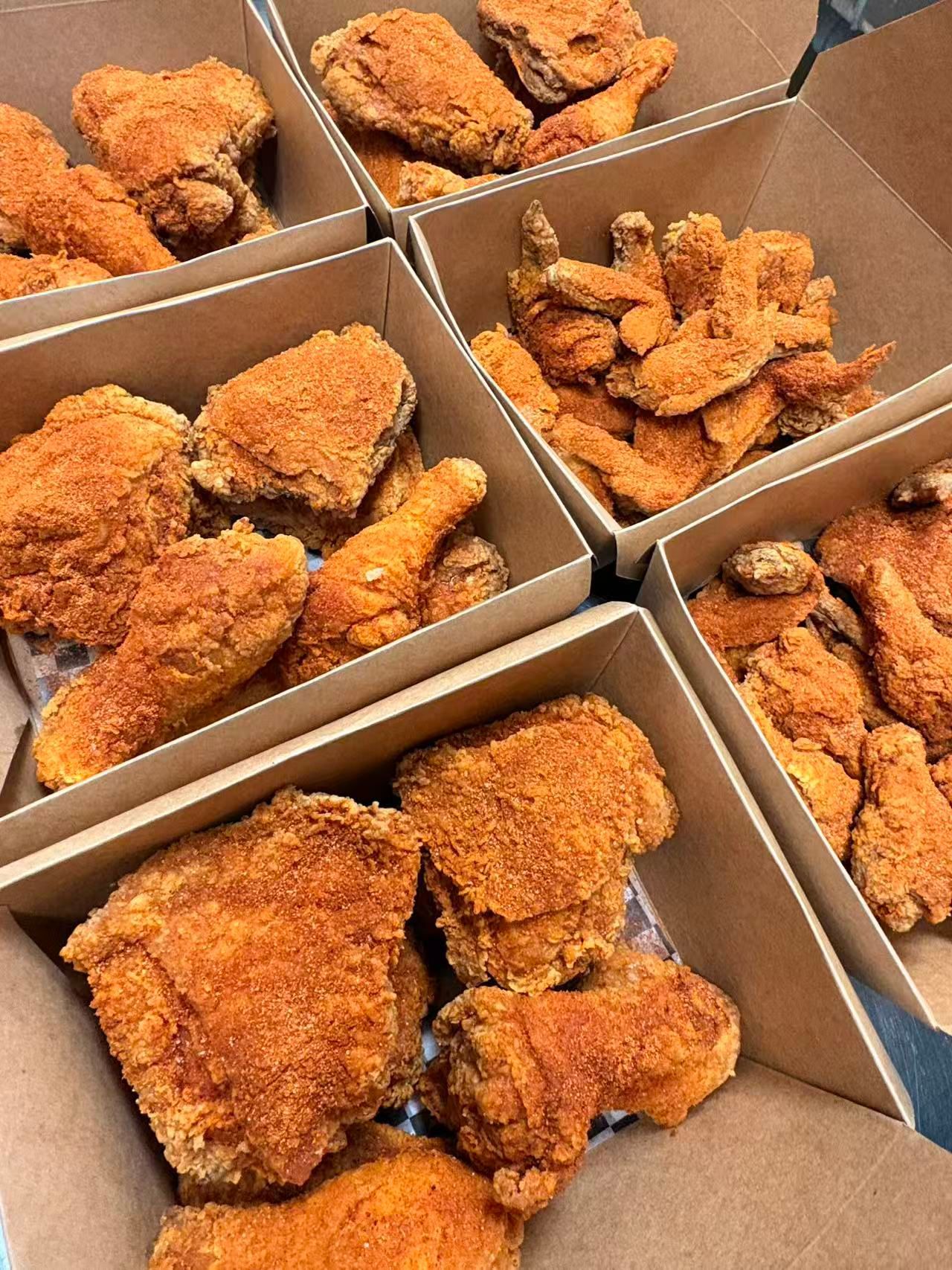 Several boxes of crispy fried chicken pieces in a takeaway container stack