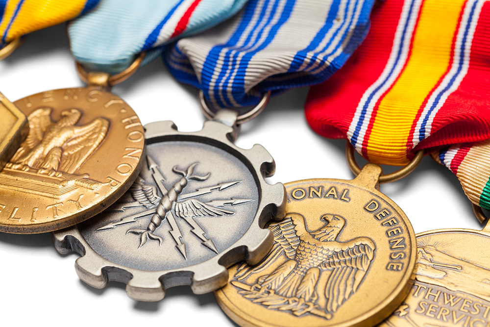 Close-up of several military medals with colorful ribbons, various shapes, and eagle designs.