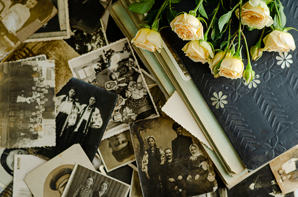 Stack of old photographs, a book, and roses.