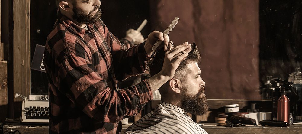 A man is getting his hair cut by a barber in a barber shop.