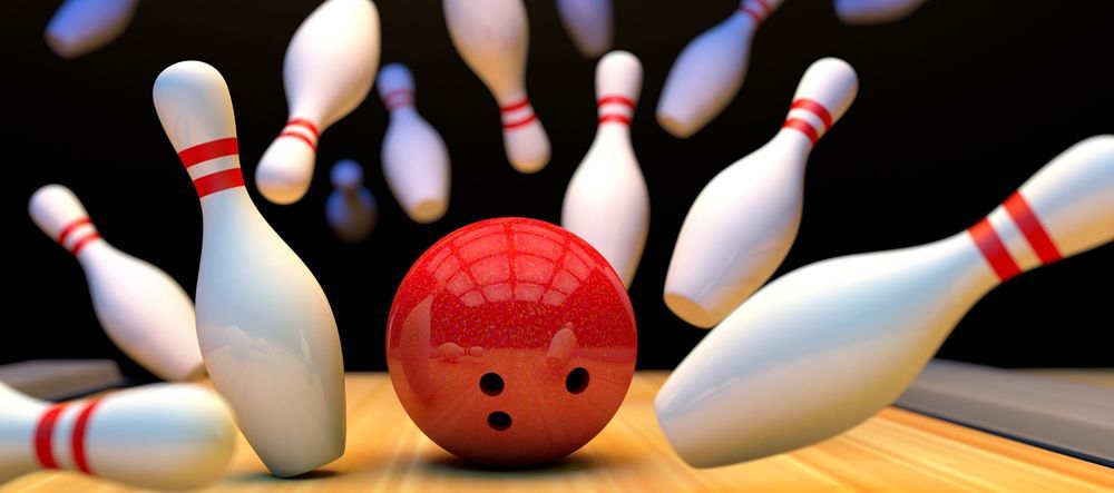 bowling ball and pins A red bowling ball is hitting white pins on a bowling alley
