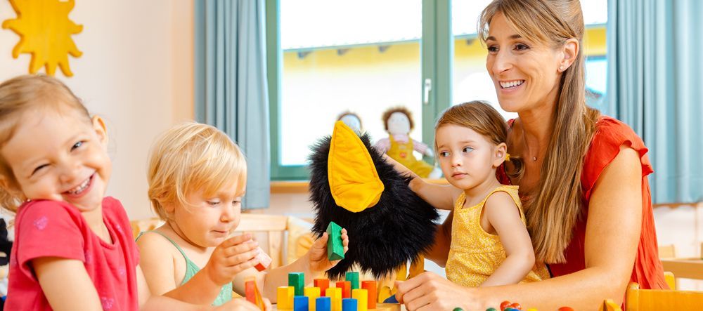 Childcare Centre a woman is smiling while playing with a group of children