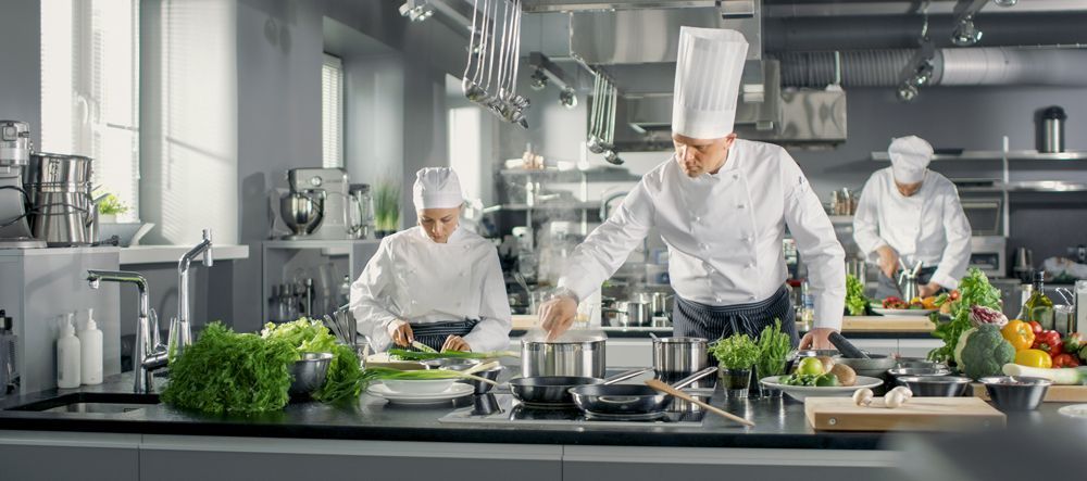 A group of chefs are preparing food in a commercial kitchen.