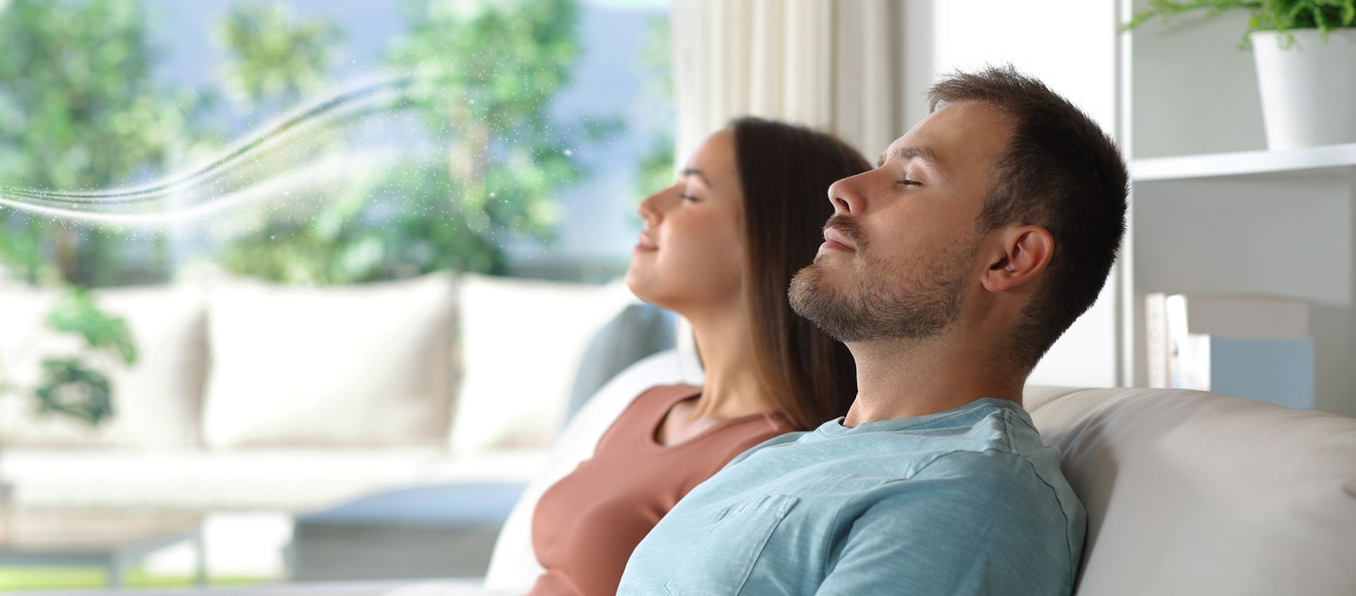 Luxury Scented Air Couple with closed eyes breathing fresh air on a sofa in a bright living room.