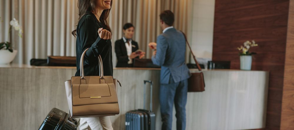 scented hotel reception A woman is standing in a hotel lobby with her luggage.