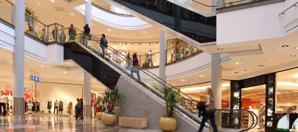 shopping centre A group of people are walking down a set of escalators in a shopping mall.