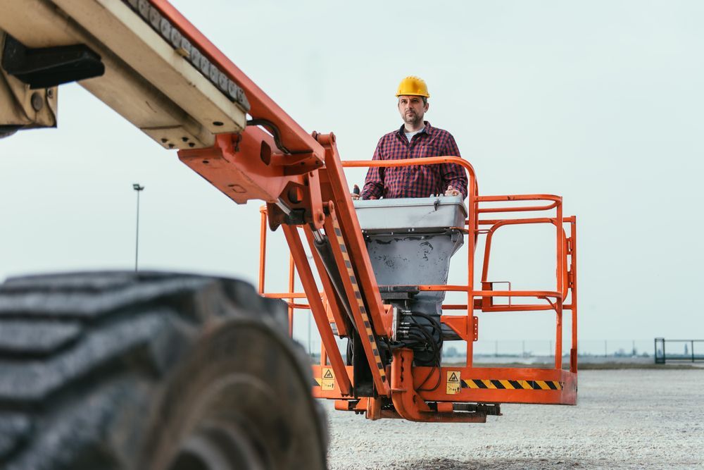 A Man in A Hard Hat Is Sitting in A Lift — Linmar Cranes & Haulage in Julia Creek, QLD