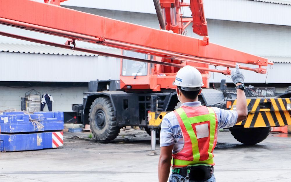 A Construction Worker Is Standing in Front of A Crane on A Construction Site — Linmar Cranes & Haulage in Northern Territory