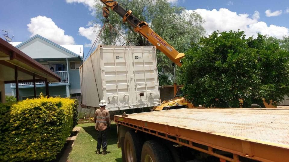 A Man Is Standing Next to A Truck that Is Being Lifted by A Crane — Linmar Cranes & Haulage in Karumba, QLD