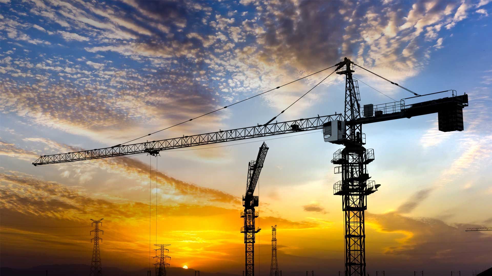 Two Construction Cranes Are Silhouetted Against a Sunset Sky — Linmar Cranes & Haulage in Northern Territory