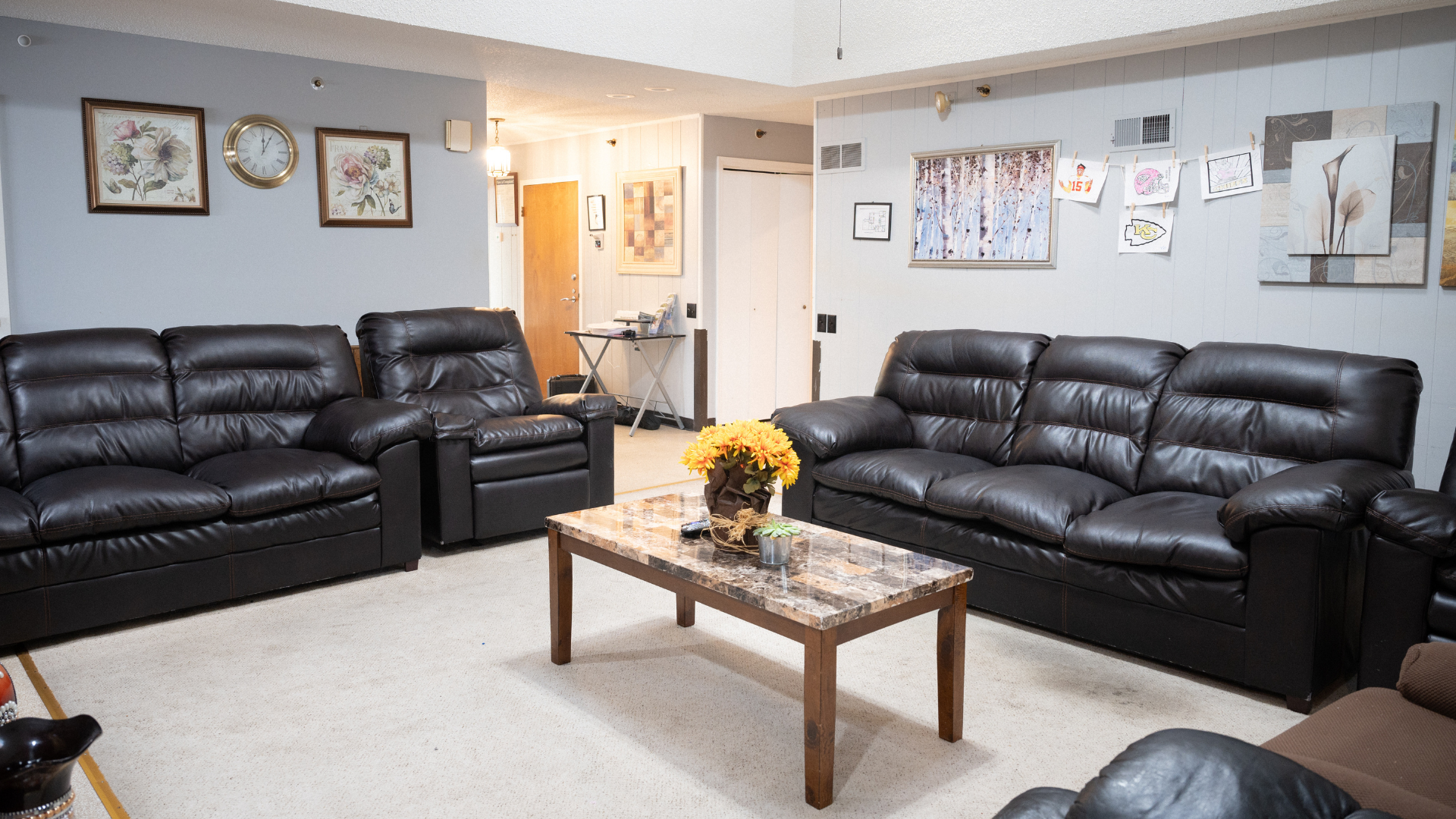Living room with two black leather sofas, coffee table, and framed wall art