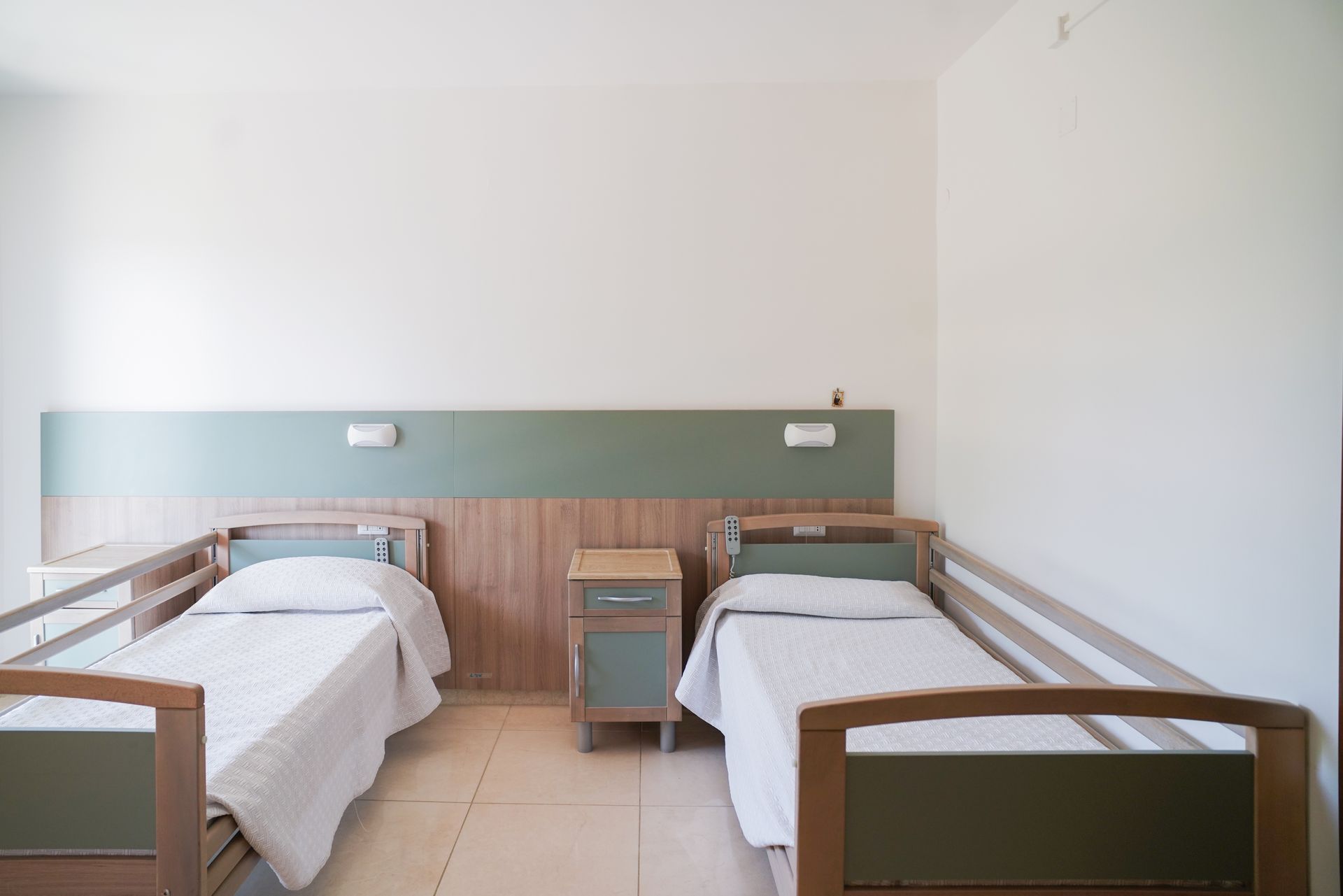 Due letti singoli in una stanza dai colori chiari con un comodino in mezzo.