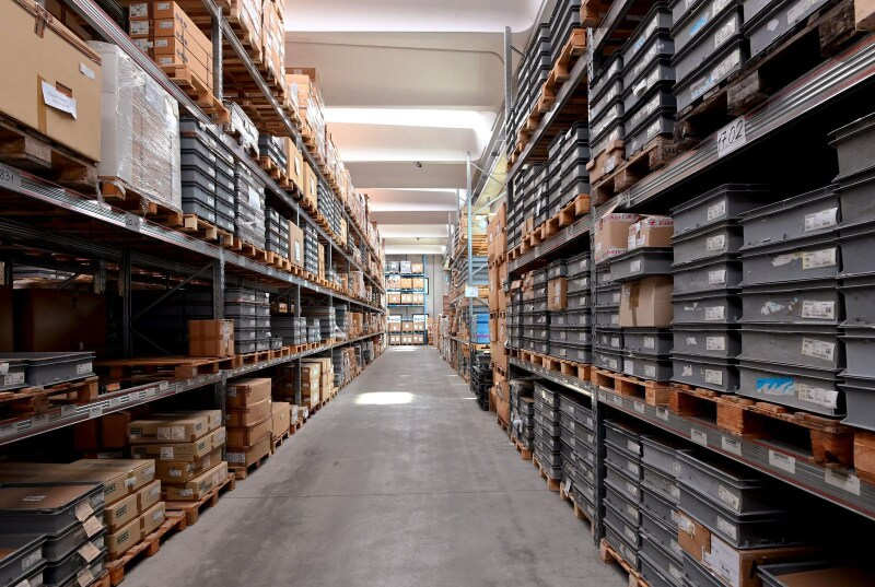 Interno di un magazzino con file di scaffali pieni di scatole e contenitori.