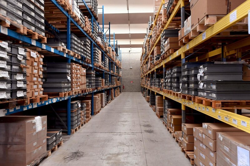 Interno del magazzino con file di scaffali pieni di scatole e materiali.