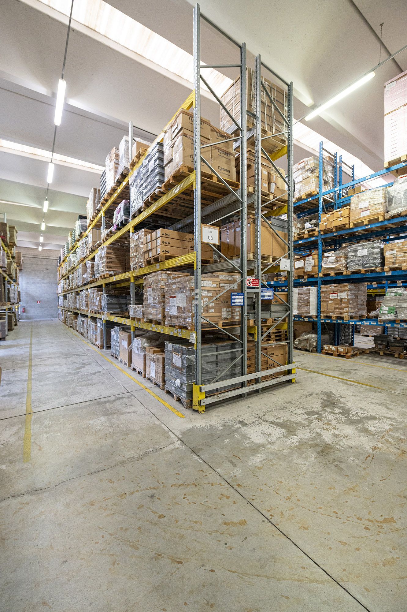 Magazzino con scaffali alti pieni di scatole e pallet.