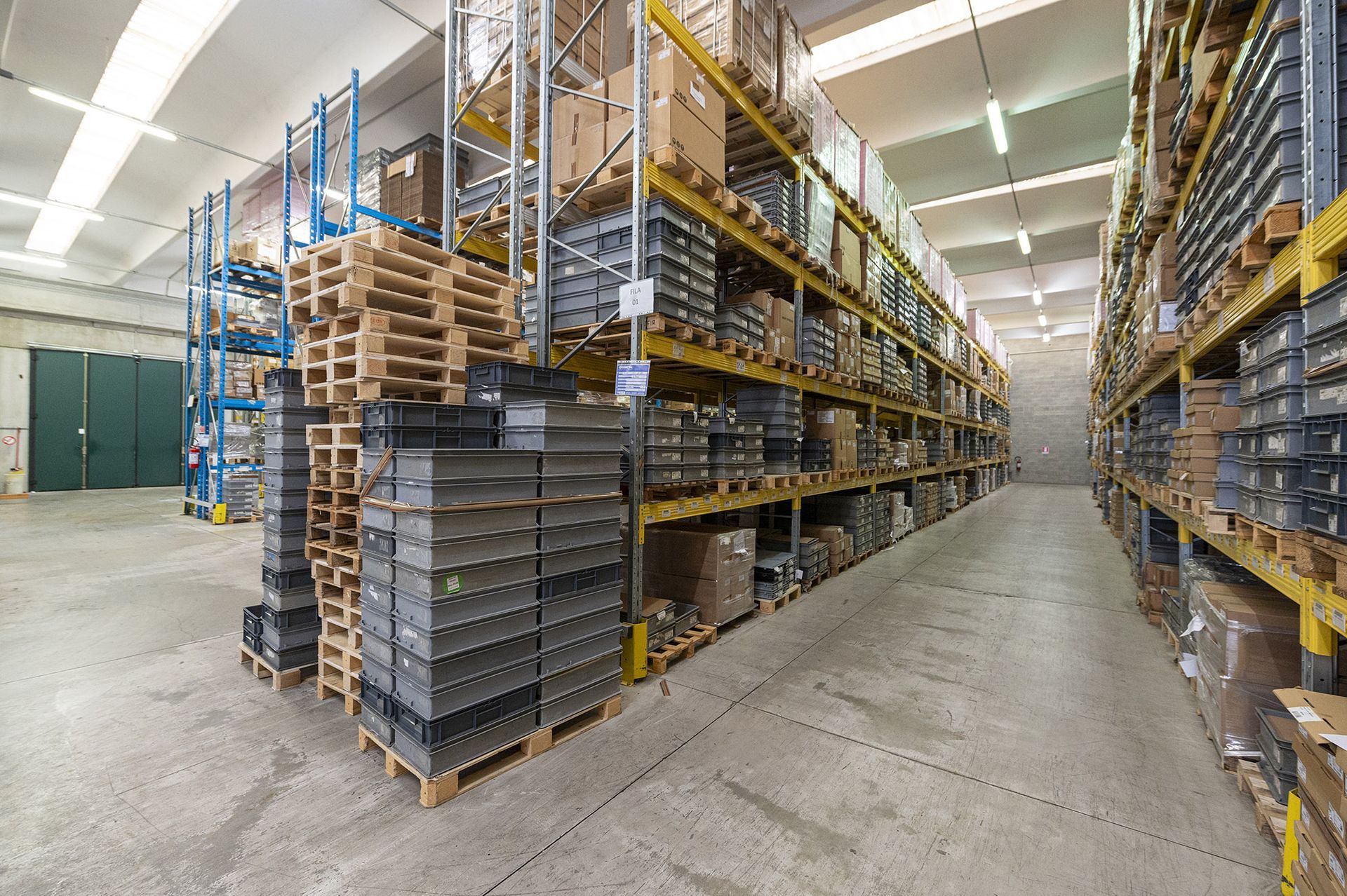 Interno del magazzino con scaffali pieni di scatole e materiali.